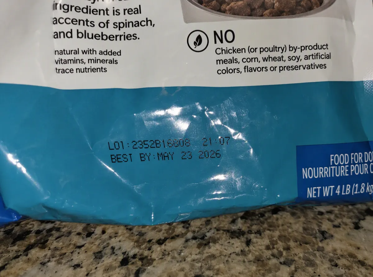 Close-up of a dog food bag's printed lot number and best by date, the codes you check against a recall notice